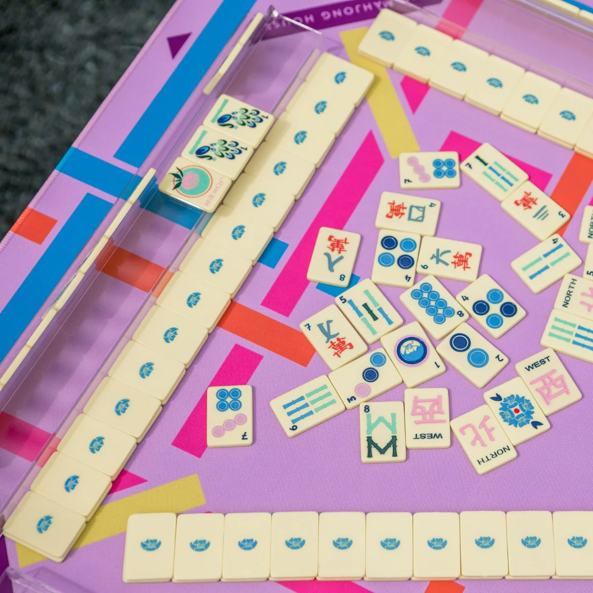 Butter Yellow travel mahjong tiles arranged on racks mid-game on a colorful mat