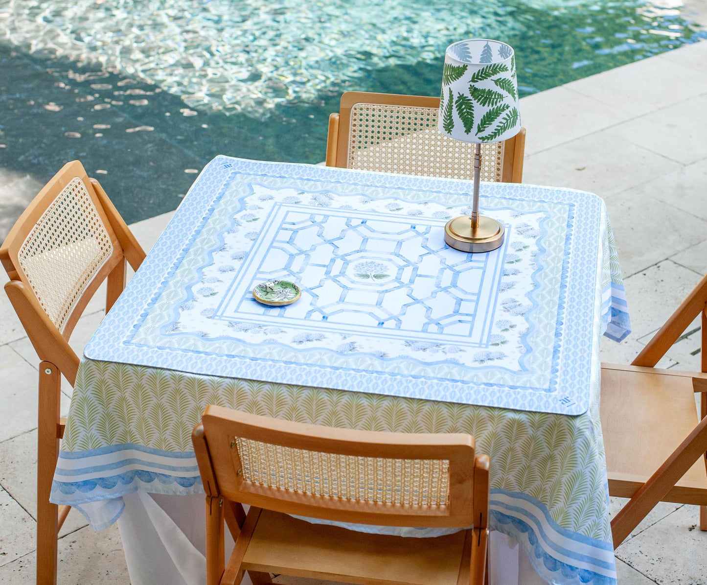 The House of Hydrangea Mahjong Mat styled on a patio table by the pool — blue and white floral mahjong table mat