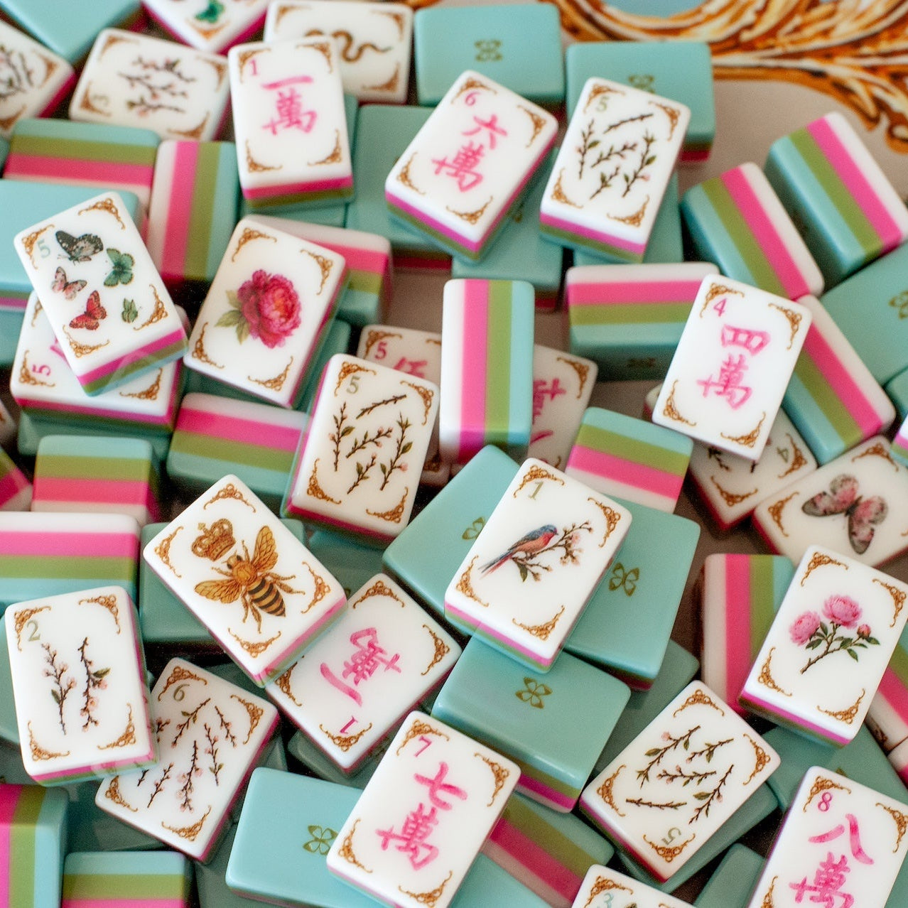 Mahj in Bloom mahjong tiles scattered — bee joker, butterfly dots, and pink craks